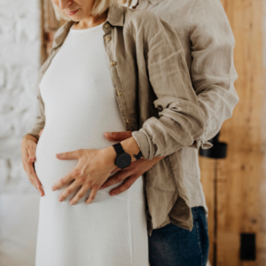 woman standing with husband hands on pregnant belly