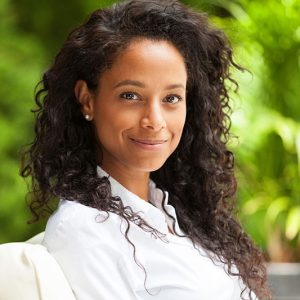 smiling black woman with long curly hair and white shirt